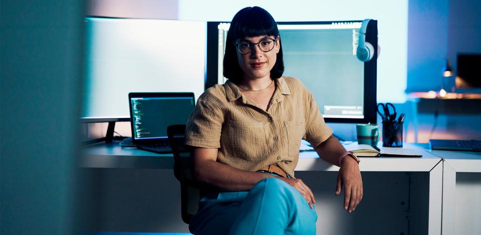 A woman sitting in front of computer screens at an office.