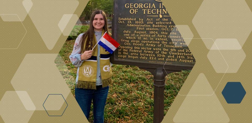 A woman holding a small Netherlands flag while standing in front of a sign that says "Georgia Institute of Technology"