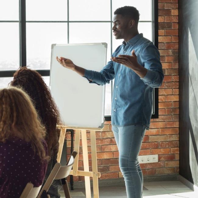 Team leader is addressing employees in loft office using white board