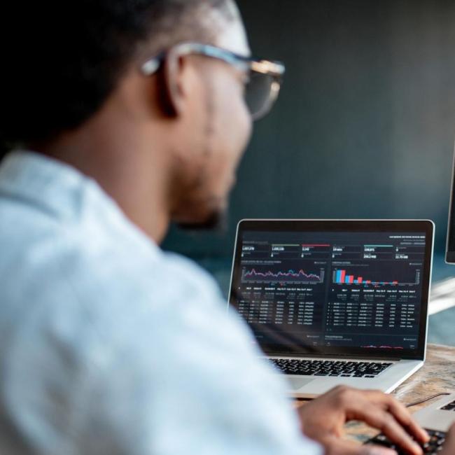 Male programmer writing program code sitting at his workplace